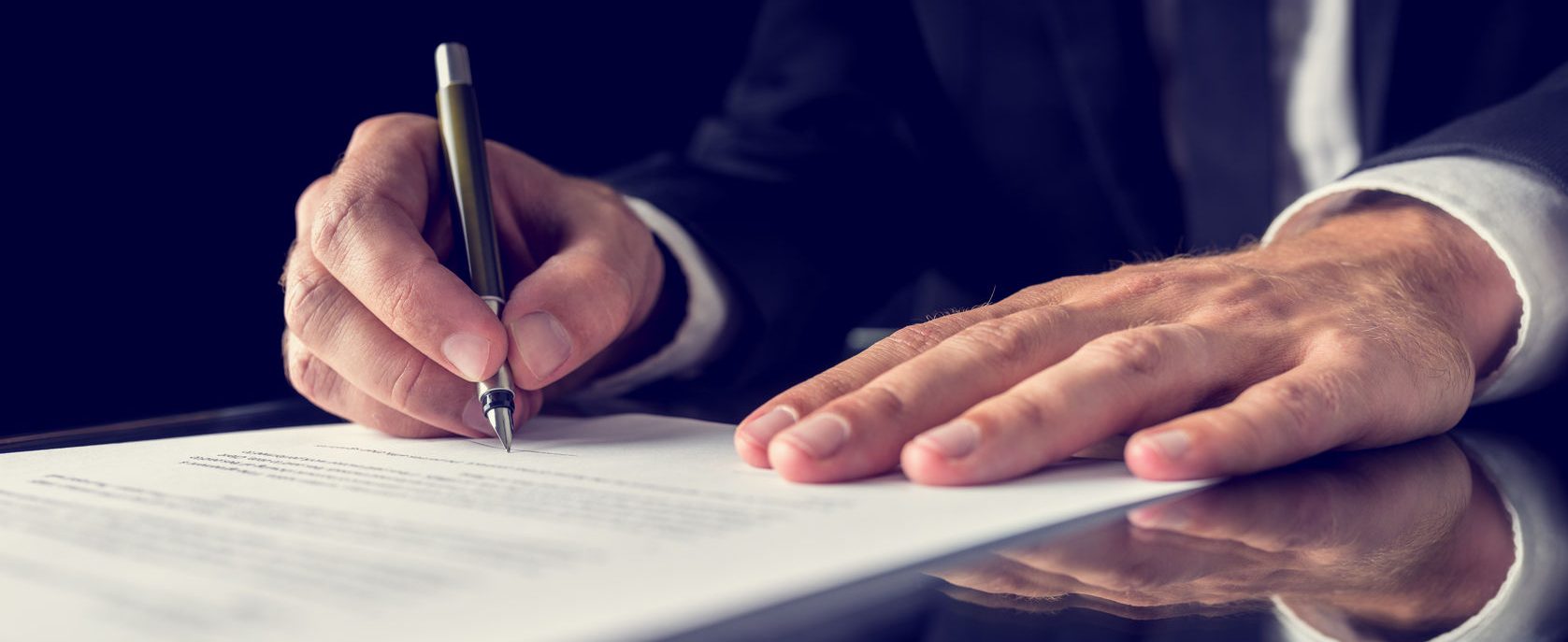 closeup of hands signing a document